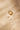 Top view of a handcrafted gold band featuring heavy, irregular texture across the surface. The pronounced grain catches light in sharp highlights and shadowed creases.